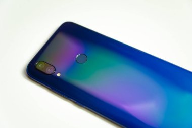 İki kamerası ve flaşlı mavi bir akıllı telefonun arkası. Beyaz arka planda renkli ışıkla aydınlatılmış.