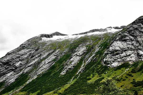Berge und Wasserfälle in Norwegen mit Schnee und grünem Gras bedeckt — Stockfoto