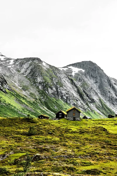 Grasdachhäuser in den Bergen Norwegens mit grünen Wiesen und einem Wildwasserfluss im Vordergrund — Stockfoto