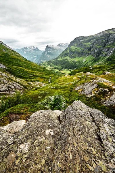 Yol üzerine yeşil mera zirveleri ve karanlık bulutlu gökyüzü kar ile Batı Norveç dağlarında — Stok fotoğraf