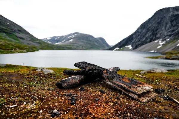 Zwęglone peaces drewna stosuje się przy ognisku w górach Norwegii z jeziorem w tle — Zdjęcie stockowe