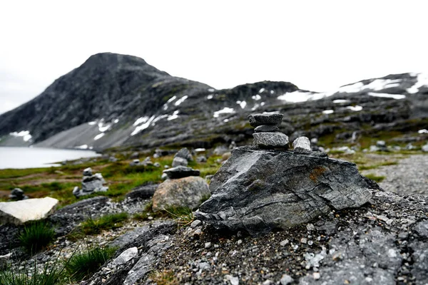 Wędrówki kamienie w centrum uwagi ze śniegiem pokryte górami i jeziorem w tle zmiękczająca w Norwegii — Zdjęcie stockowe