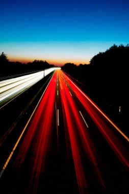 Kırmızı ve beyaz ışık yollar ve arka planda renkli bir gün batımı ile Almanya Gelsenkirchen A2 otoyolunun dikey uzun pozlama görüntü