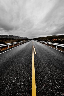 geniş açık bir çayır ve dağlar göz kış döneminde karanlık bulutlu gökyüzü altında güzel doğa ile görebilirsiniz kadarıyla uzanan bir asfalt Otoban yol ile görüntü     