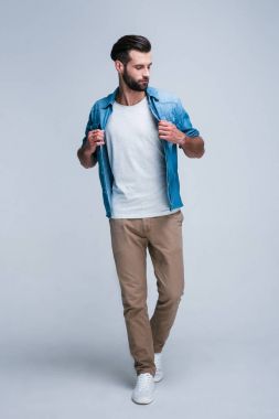 Son dokunmatik ups. Tam uzunlukta yakışıklı genç adamın gömleğini beyazlara karşı suç işliyor arka plan ayakta iken ayarlama