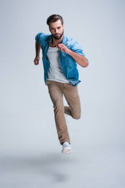 Beş dakika içinde olacak! Kamera whilerunning beyaz bir arka plana dayanır bakarak yakışıklı genç adam tam uzunlukta