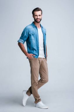 Büyüleyici ve rahat. Yakışıklı genç adamın smilewhile ayakta beyaz arka plan ile kameraya bakarak tam uzunlukta