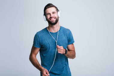 Küçük bir dans. Yakışıklı genç adam kulaklık gülümseme whilestanding beyaz arka plan ile müzik dinlemek