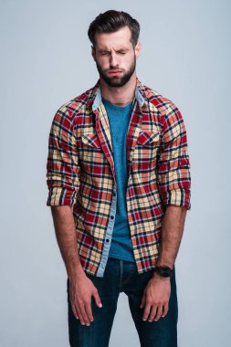 Korkmuş ve yakışıklı. Yakışıklı genç adam gözleri duran beyaz arka plan karşı kapalı tutmak Kareli gömlekli