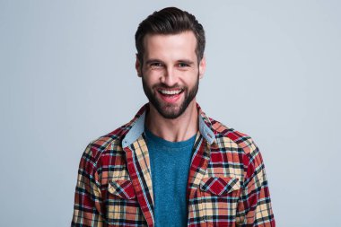 Şimdiye kadar gördüğün en iyi gülüşünüzü gösterin. Beyaz arka plan karşı dururken gülümseme ile kameraya bakarak yakışıklı genç adam portresi