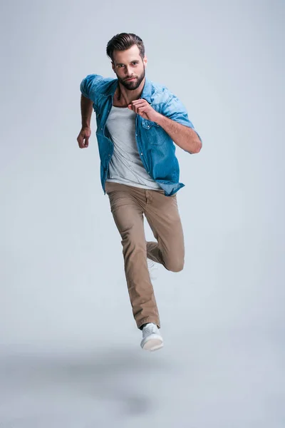 Beş dakika içinde olacak! Kamera whilerunning beyaz bir arka plana dayanır bakarak yakışıklı genç adam tam uzunlukta