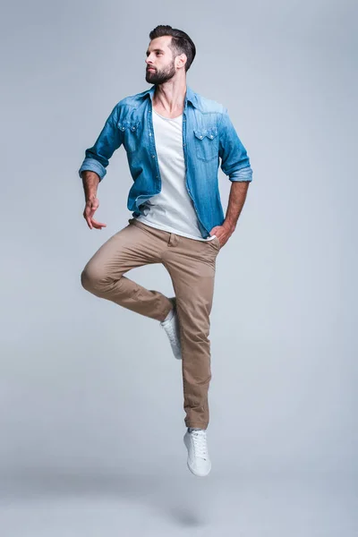 Bir tüy gibi hissediyorum! Uzak jumpingagainst beyaz arka planı seyir yakışıklı genç adam tam uzunlukta