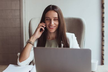Bizim toplantı muhteşem oldu! Güzel genç işkadını üstünde hareket eden telefon ofis masasında otururken gülümseme ile konuşmak