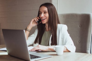 Seni dinlemek çok güzel! Güzel genç işkadını üstünde hareket eden telefon ofis masasında otururken gülümseme ile konuşmak