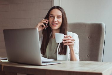 Yarın 12'de görüşürüz! Güzel genç işkadını üstünde hareket eden telefon ofis masasında otururken gülümseme ile konuşmak