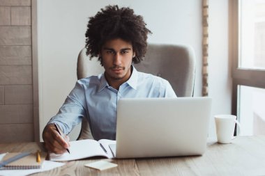 İş yerinde yoğunlaşmıştır. Yakışıklı genç işadamı ofis masasında otururken bir şey yazma