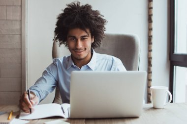 Onun iş adlı kendinden emin. Yakışıklı genç işadamı athis Ofis Masası otururken bir şey yazma