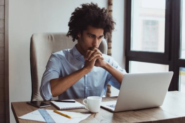 Çift her şeyi kontrol edin! Yakışıklı genç işadamı ofis masasında otururken diz üstü kullanarak