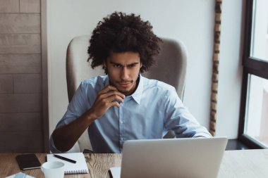 Bu rapor içinde bakmak gerekir. Yakışıklı genç işadamı ofis masasında otururken diz üstü kullanarak