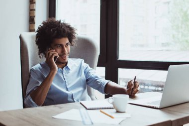 Harika bir rapordur. Hareket eden telefon ofis masasında otururken gülümseme ile konuşurken yakışıklı genç işadamı