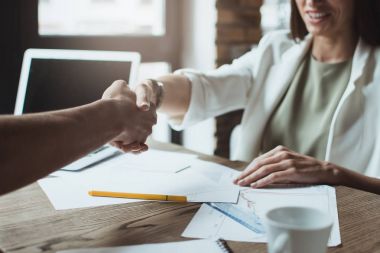İstihdam edilmesini! Genç işkadını ortağı ofis masasında otururken gülümseme ile elini sıkarken close-up parçası