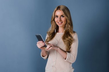 En sevdiği şarkı. Güzel genç kadın cep telefonu tutan ve gülümseme duran siyah arka plan ile kameraya bakarak kulaklık