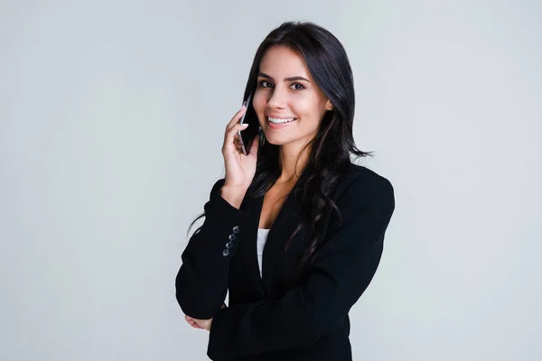 Neşeli iş kadını. Onun smartphone üzerinde konuşmak ve gülümseme duran beyaz arka plan ile kameraya bakıyor güzel genç iş kadını