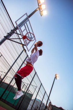Gol! Tam uzunlukta dikiz genç adam açık havada basketbol sahasına basketbol oynarken spor giyim