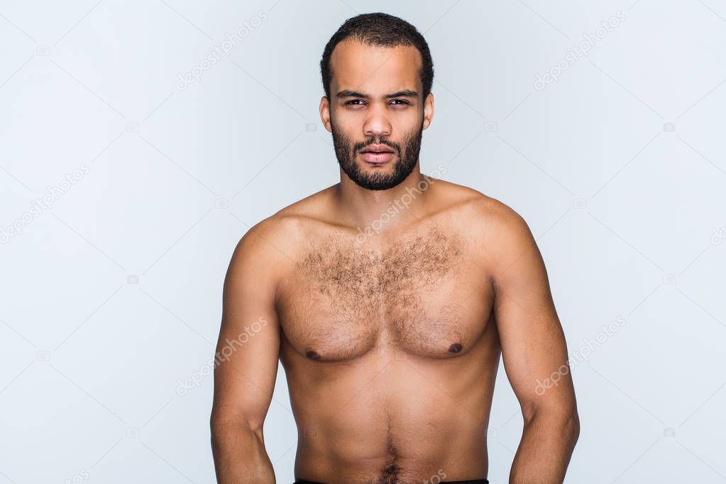 Macho man. Portrait of handsome shirtless young black man looking at camera while standing against white background