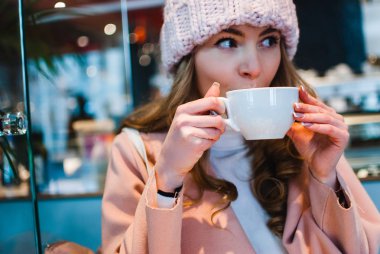 O zaman kışın sıcak kakao bir fincan daha iyi ne olabilir? Uzağa bakarak ve kafede kahve içme pembe ceket güzel genç kadın portresi