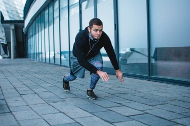 Hazır, başla! Spor giyim sanayi kenti görünümü karşı çalıştırmak hazırlanıyor genç adam tam uzunlukta