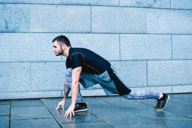 Başlarım. Spor giyim sanayi kenti görünümü karşı çalıştırmak hazırlanıyor genç adam tam uzunlukta yan görünüm