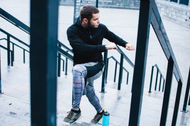 Maraton hazır. Spor giyim sanayi kenti görünümü karşı germe yapmak genç adam tam uzunlukta