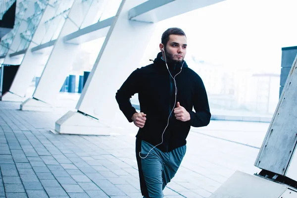 Moving forward every day. Handsome young man in sportswear jogging against industrial city view