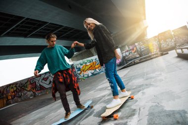 Aşırı ders. Genç yakışıklı erkek arkadaşı longboard kaykay Park açık havada binmek kullanmayı öğretmek