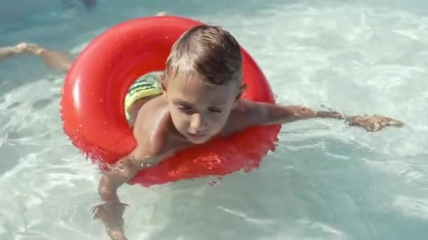 O menino flutua em uma piscina inflável na piscina — Vídeo de Stock