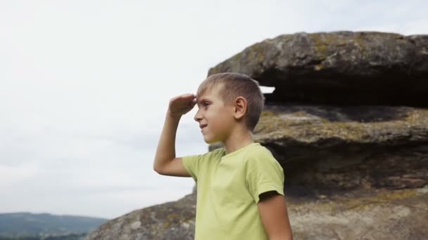 El niño se para en la cima de la montaña y mira los prismáticos — Vídeos de Stock