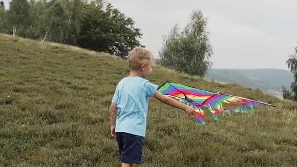 De jongen loopt en lanceert een slang in de bergen — Stockvideo