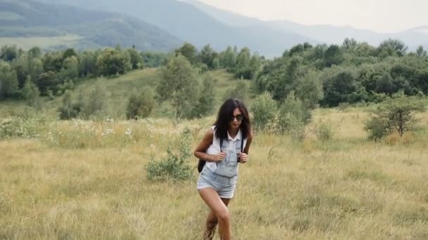 Девушка путешествует по горам с рюкзаком — стоковое видео