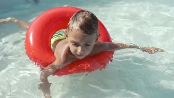 El chico flota en una piscina inflable en la piscina — Vídeos de Stock