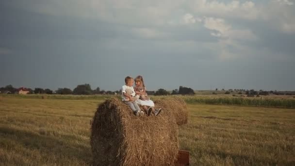 Dvě malé děti sedí na balíků se slámou a hrát hračky. Šťastné a vtipné děti. — Stock video
