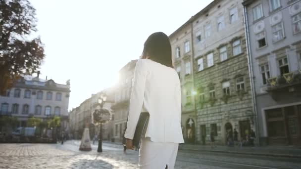 Una joven mujer de negocios caminando por la ciudad con una carpeta de documentos — Vídeos de Stock