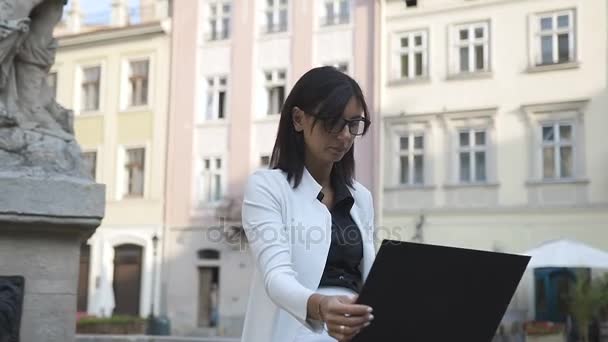 Een jonge zakenvrouw in bedjes werk op een computer in de stad — Stockvideo