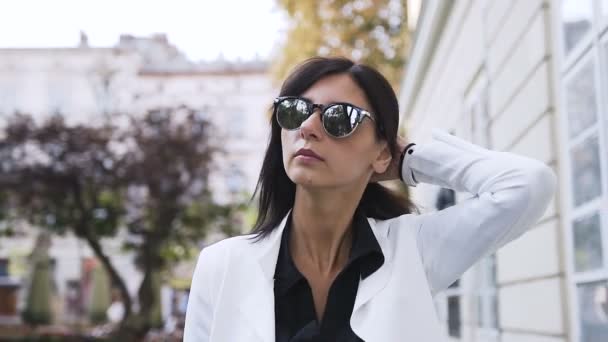 Joven mujer de negocios en las gafas va alrededor de la ciudad — Vídeos de Stock