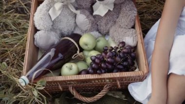 Küçük bir kız bir yeşil elma saman sepetten alır. Meyveler: üzüm ve elma, suyu