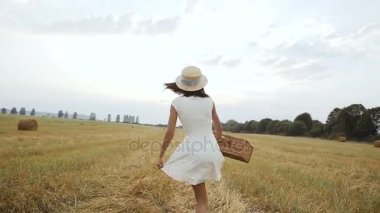 Alan. Gün batımı. Genç bir kız olan bir hasır şapka ve bir bavul alana gider.