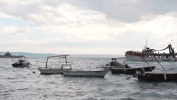Большой корабль, наполненный людьми, плавающими в открытом море и показывающими людям побережье Макарска — стоковое видео