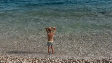 Çocuk Adriyatik Denizi kıyısında duruyor ve doğanın güzelliği hayran