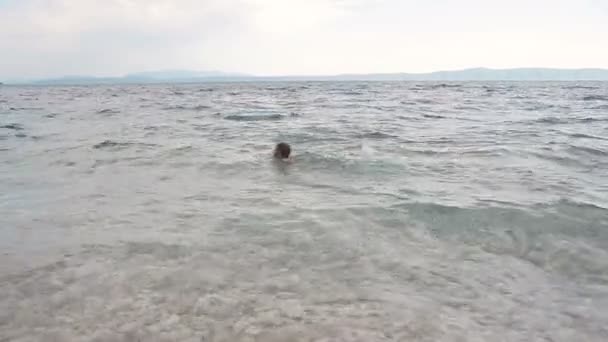 小男孩快乐是在亚德里亚海中的游泳。海中的波浪。克罗地亚 — 图库视频影像