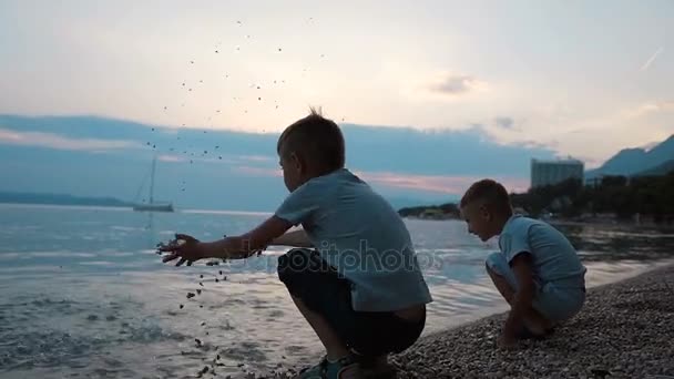 Two young boys on the Adriatic coast funny throw stones at the sea. Dalmatia. Croatia — Stock Video